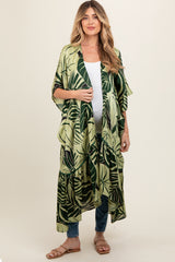 woman wearing a green tropical print maternity kimono over a white top and jeans
