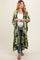 woman wearing a green palm leaf print maternity kimono over a white tank top and blue jeans, showcasing her baby bump