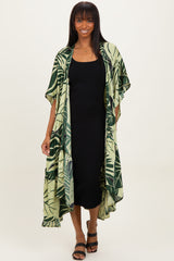 woman wearing a green leaf patterned kimono over a black midi dress and black strappy sandals