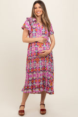 woman wearing a colorful floral maternity dress with ruffled sleeves and holding her baby bump