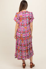 woman wearing a colorful floral print maternity dress with ruffle sleeves and a flowy skirt, showing her baby bump