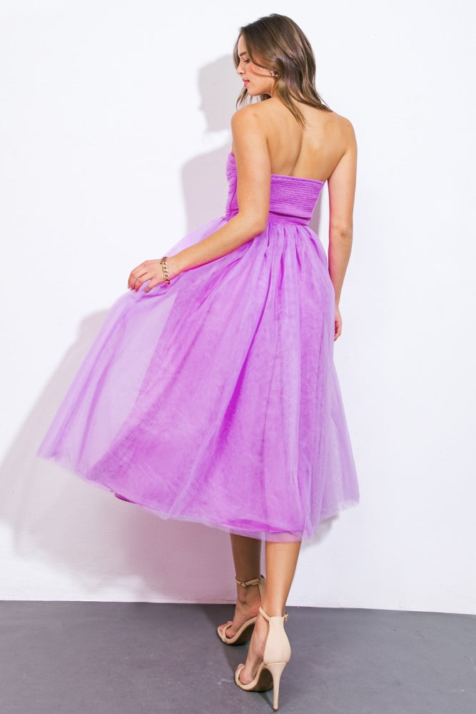 woman wearing a strapless purple tulle midi dress, twirling with a flowy skirt and a fitted bodice