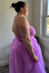 woman wearing a strapless light pink ball gown with a fitted bodice and tulle skirt, side view showcasing tattoos