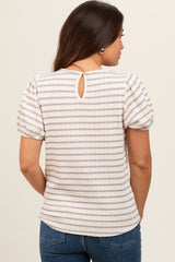 woman wearing a cream and beige striped maternity top with puff sleeves and a back keyhole detail