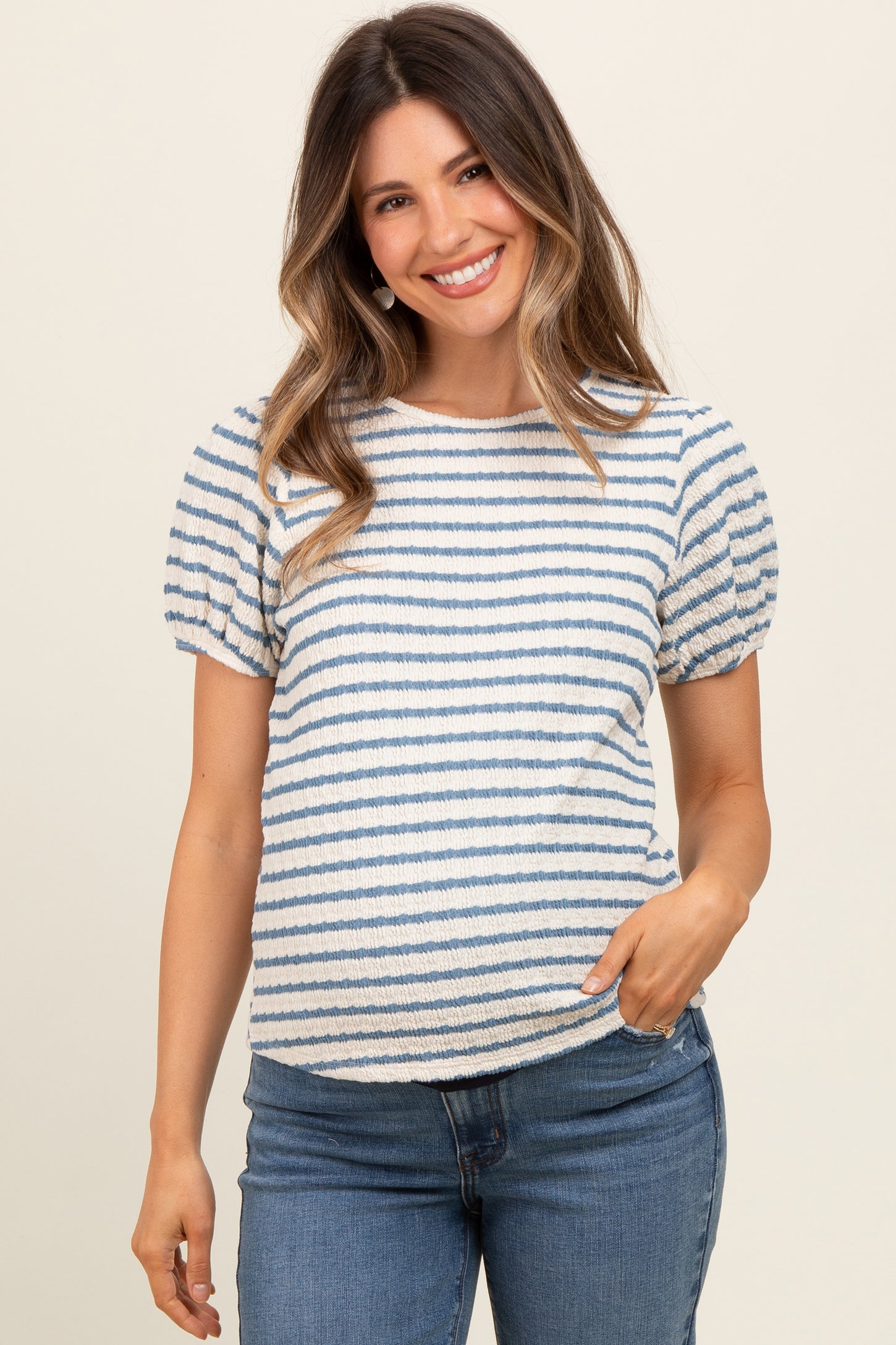 woman wearing a striped maternity top with puff sleeves and a visible baby bump, paired with jeans
