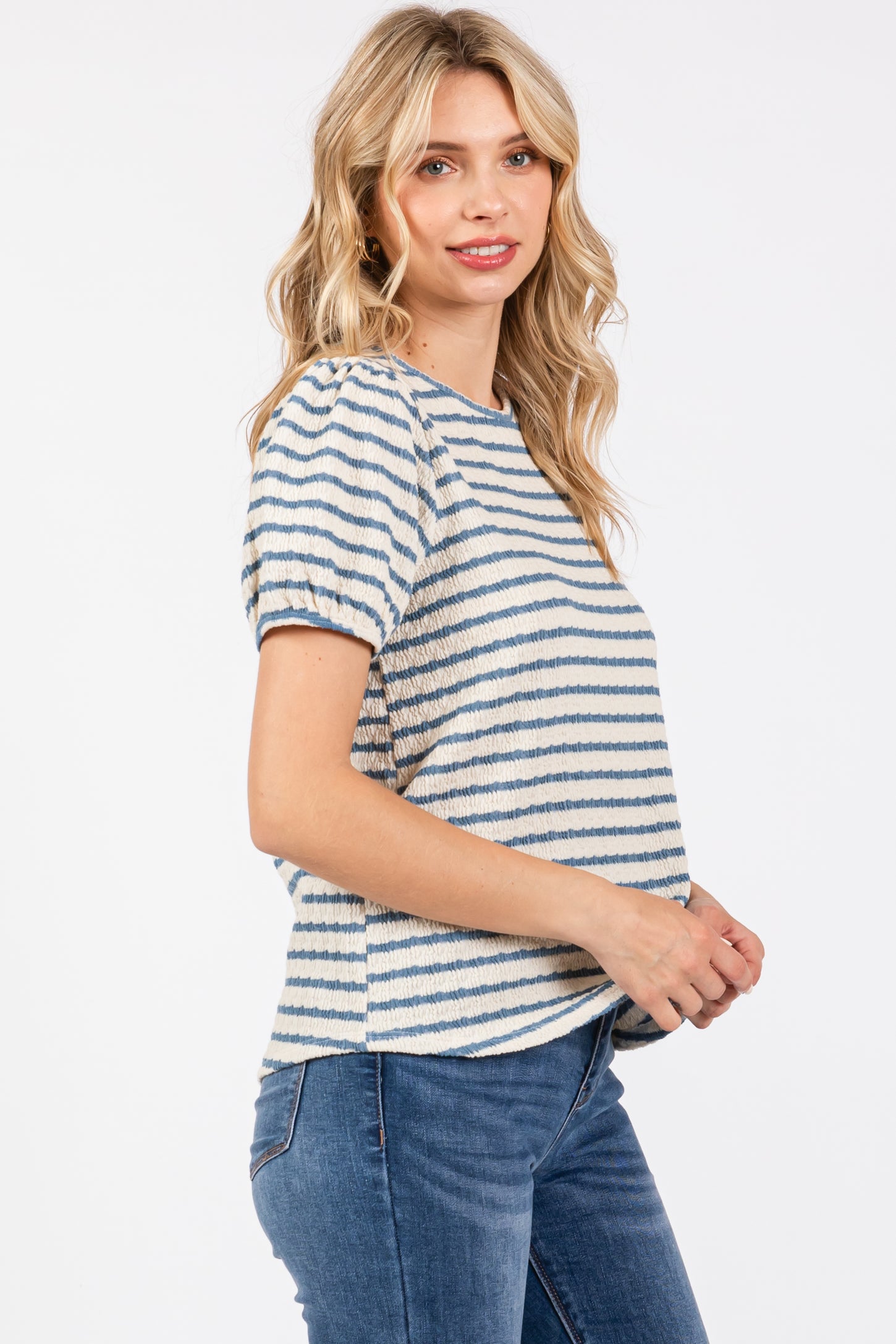 woman wearing a cream and blue striped short sleeve top with puff sleeves and paired with blue jeans