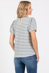 woman wearing a striped short sleeve top with puffed sleeves and a keyhole back, paired with jeans