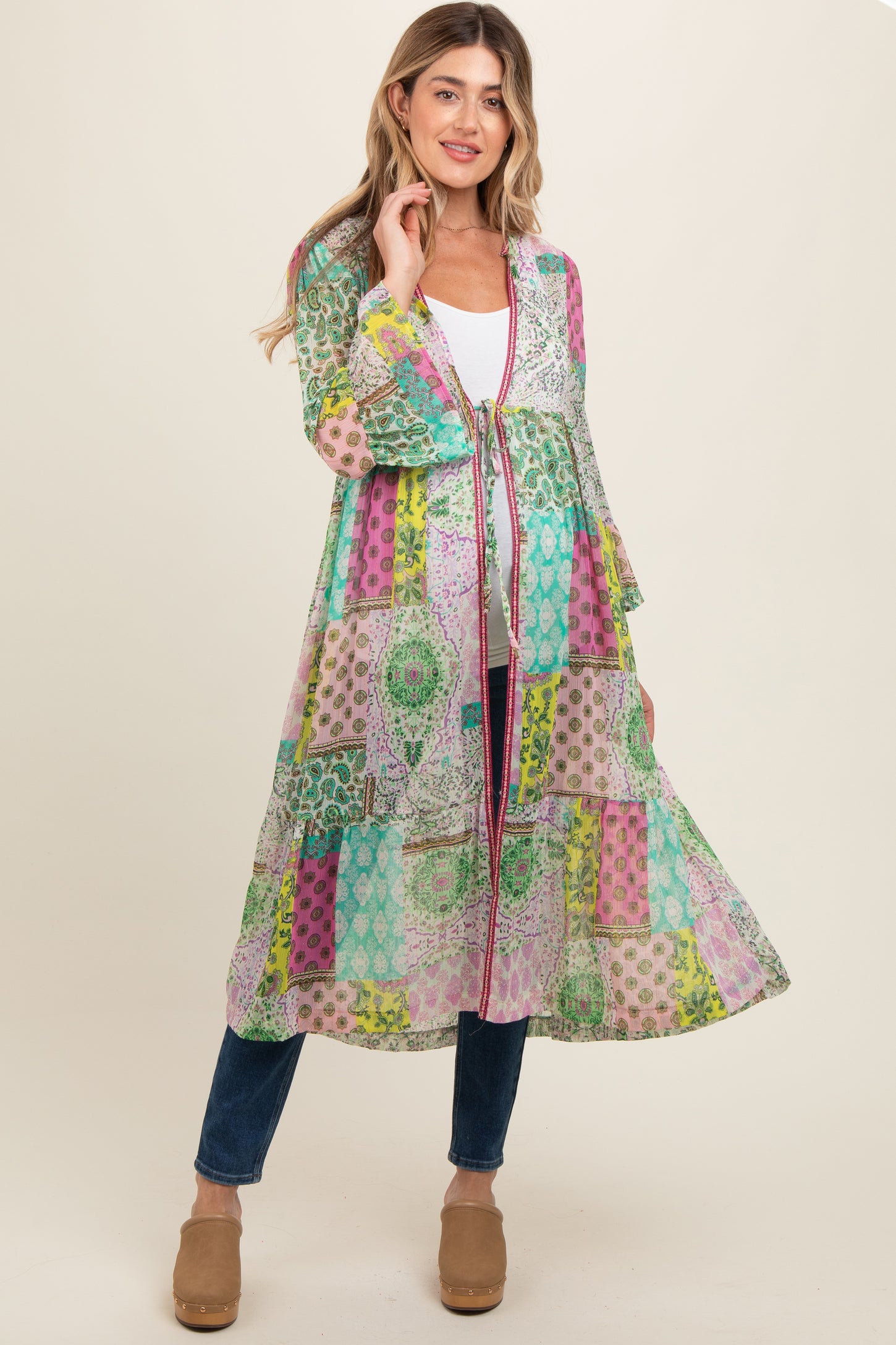 woman wearing a colorful patterned maternity kimono over a white top and blue jeans, with flowing sleeves and open front