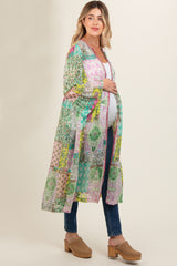 woman wearing a colorful patterned maternity kimono over a white top and blue jeans, showing her baby bump