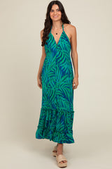 woman wearing a green and blue leaf print maxi dress with a halter neckline and ruffled hem