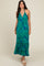 woman wearing a green and blue leaf print maxi dress with a halter neckline and ruffled hem