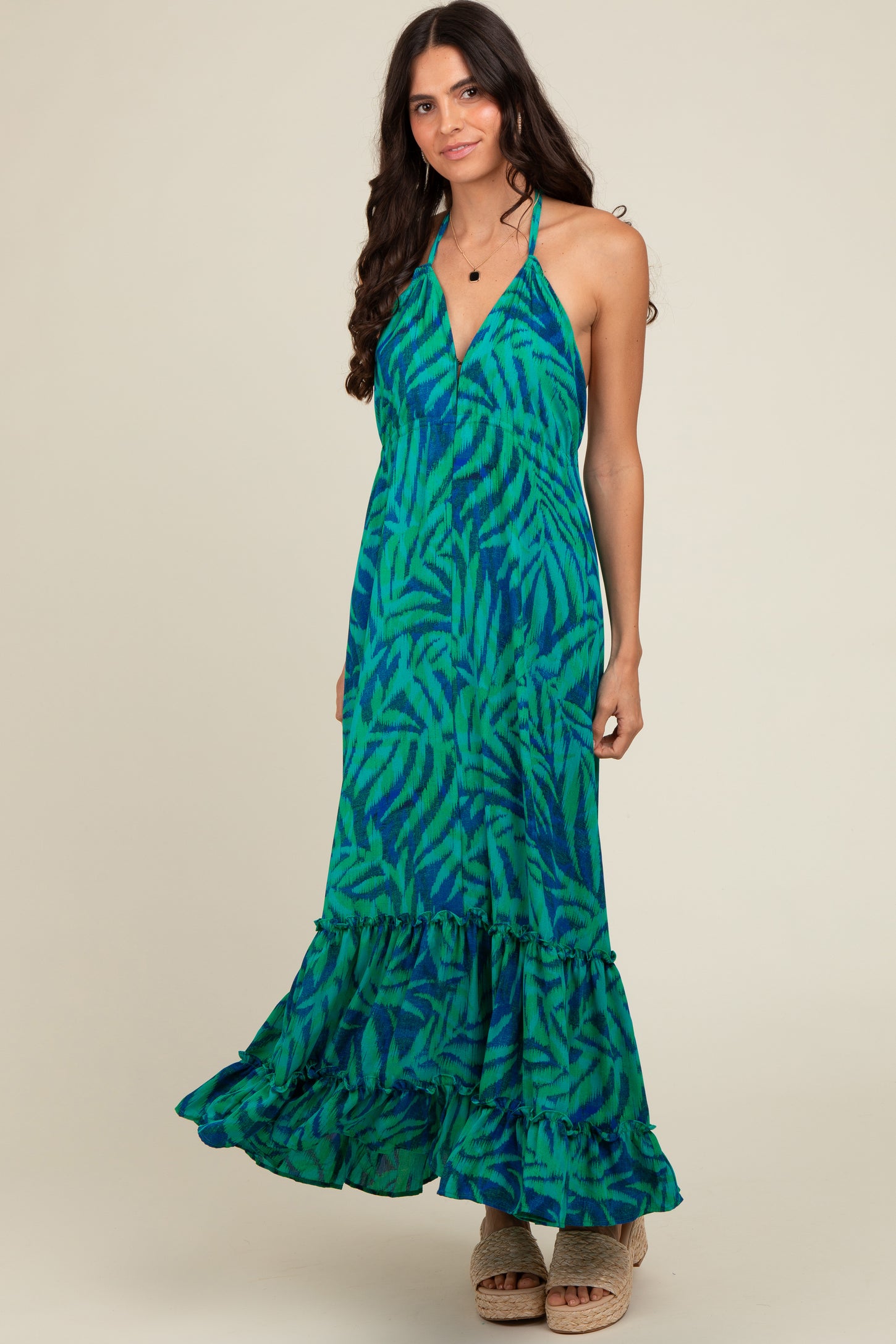 woman wearing a green and blue patterned maxi dress with a halter neck and ruffle hem