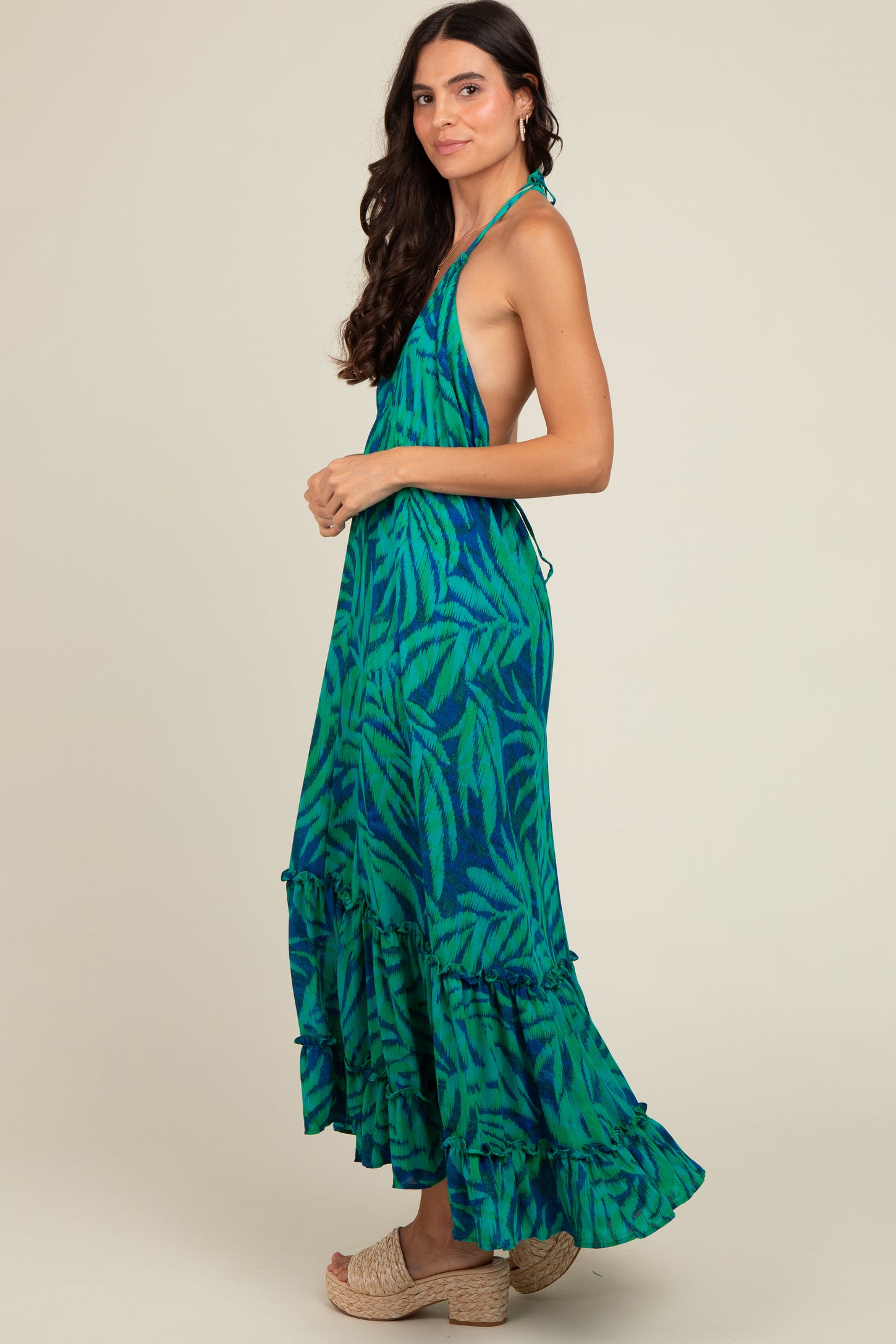 woman wearing a green and blue patterned maxi dress with a halter neck and ruffled hem