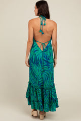 woman wearing a green and blue tropical print maxi dress with a tie-back detail and ruffled hem