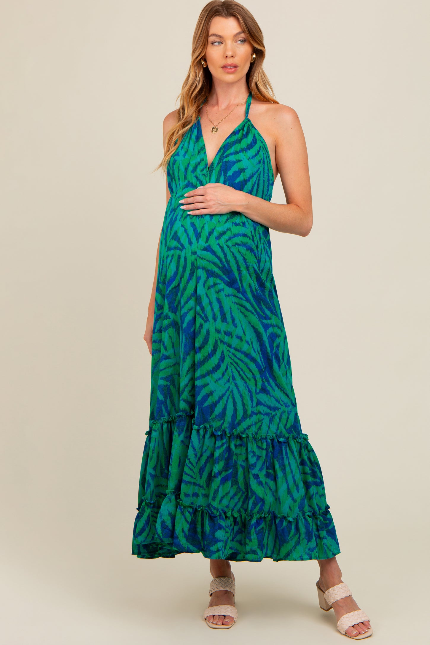 woman wearing a green and blue patterned maternity maxi dress, holding her baby bump