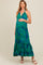 woman wearing a green and blue patterned maternity maxi dress, holding her baby bump