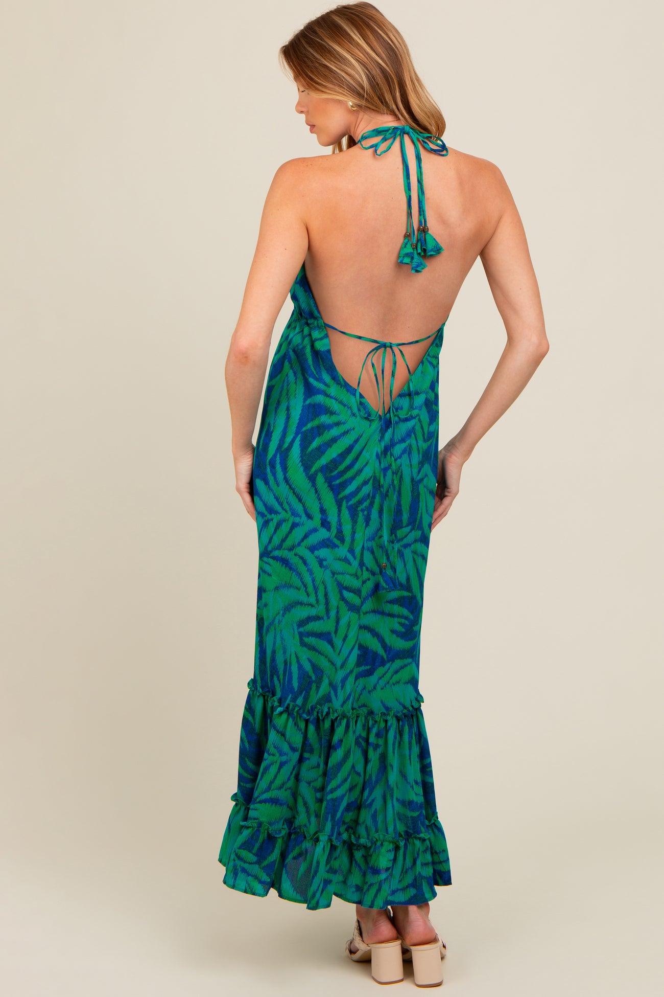 woman wearing a backless green and blue tropical print maternity dress with a ruffled hem