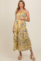 woman wearing a yellow tropical print maternity dress with a halter neck and a baby bump visible