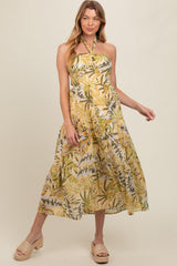 woman wearing a yellow floral maternity maxi dress with a halter neck and tiered skirt