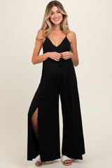 woman wearing a black maternity jumpsuit with a tie waist and side slits, showcasing her baby bump