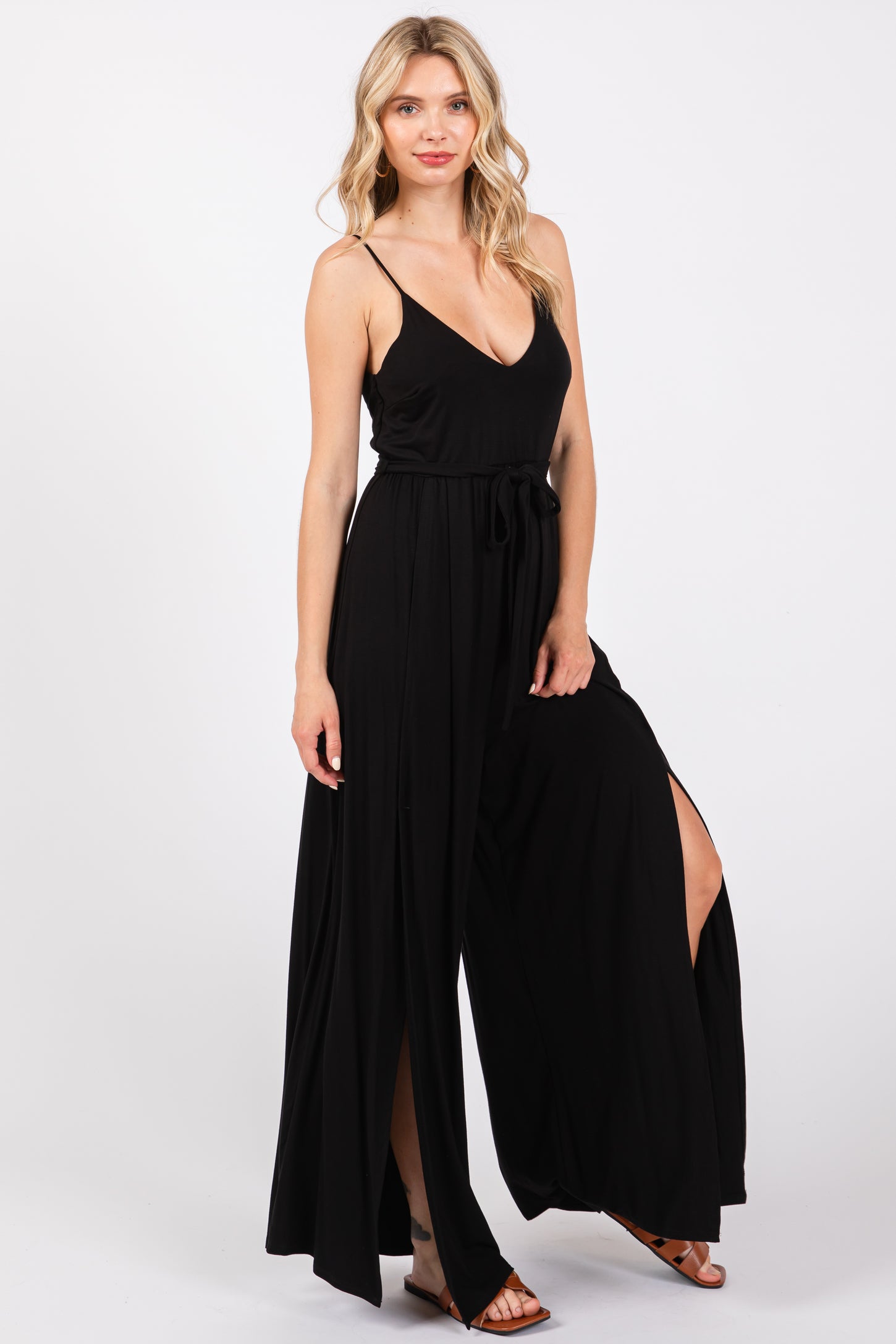 woman wearing a black maxi dress with a deep v-neck, thin straps, and side slits, styled with a tie belt