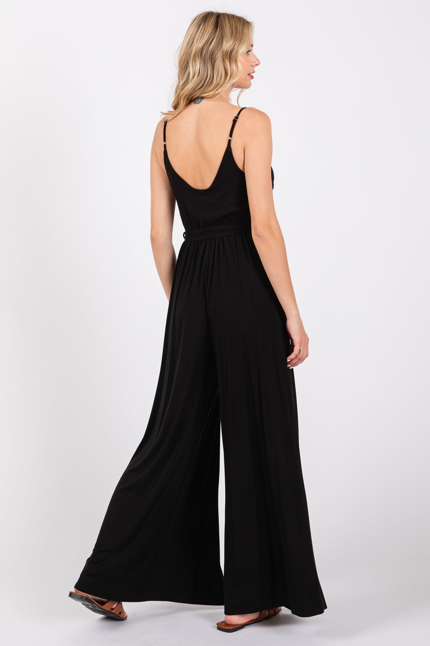 woman wearing a black wide-leg jumpsuit with a low back and thin straps, viewed from the back