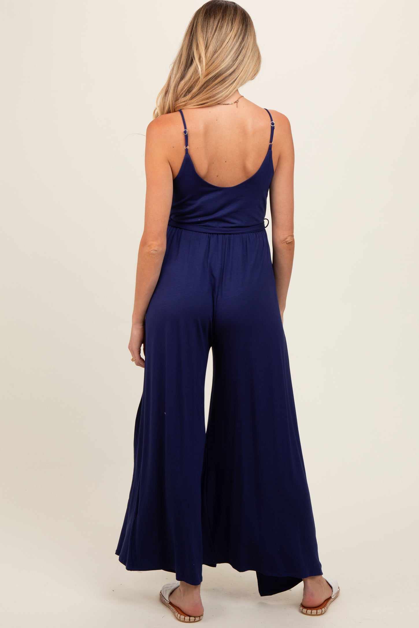 woman wearing a navy blue maternity jumpsuit with a flowy wide leg and adjustable spaghetti straps