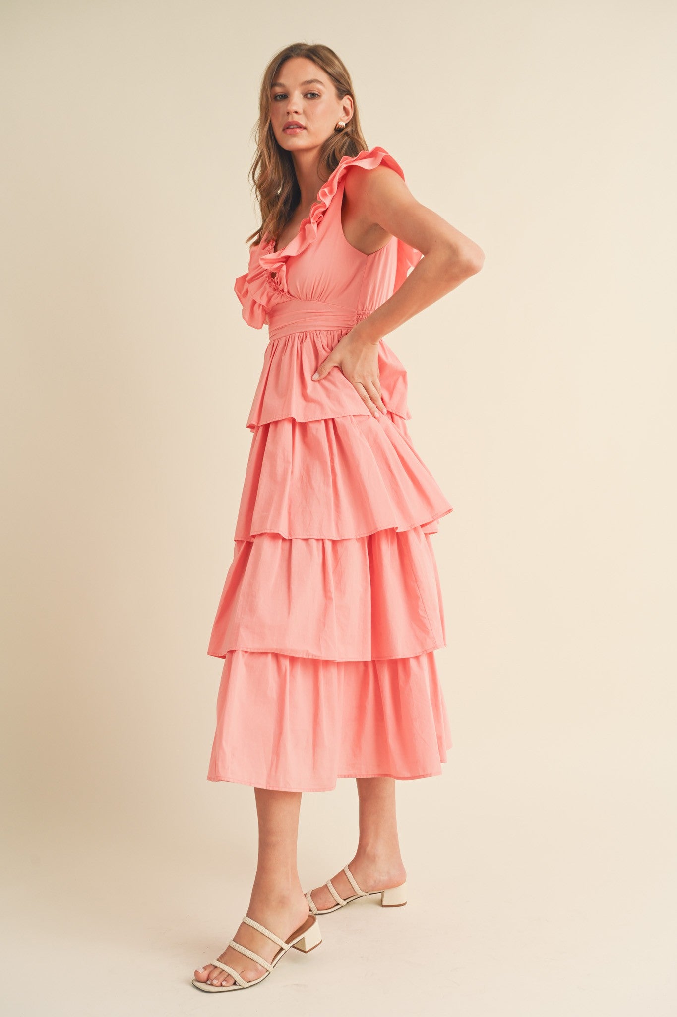 woman wearing a pink tiered midi dress with ruffles and a flared silhouette