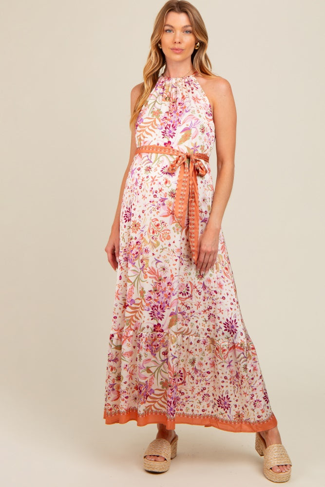 woman wearing a floral maxi maternity dress with halter neck and waist tie, showcasing her baby bump