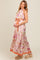 woman wearing a floral print maternity maxi dress with a halter neck and tied waist, showing her baby bump