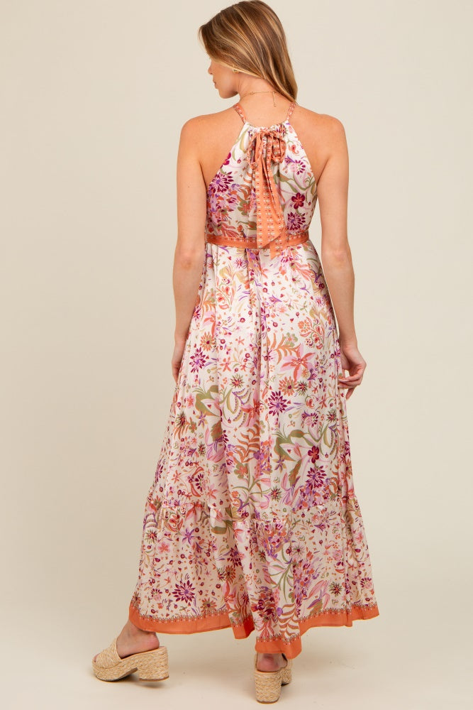woman wearing a floral maxi maternity dress with a halter neck and back tie detail, showing a baby bump