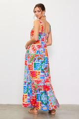 woman wearing a colorful patterned maxi dress with a flared hem and adjustable straps, seen from the back