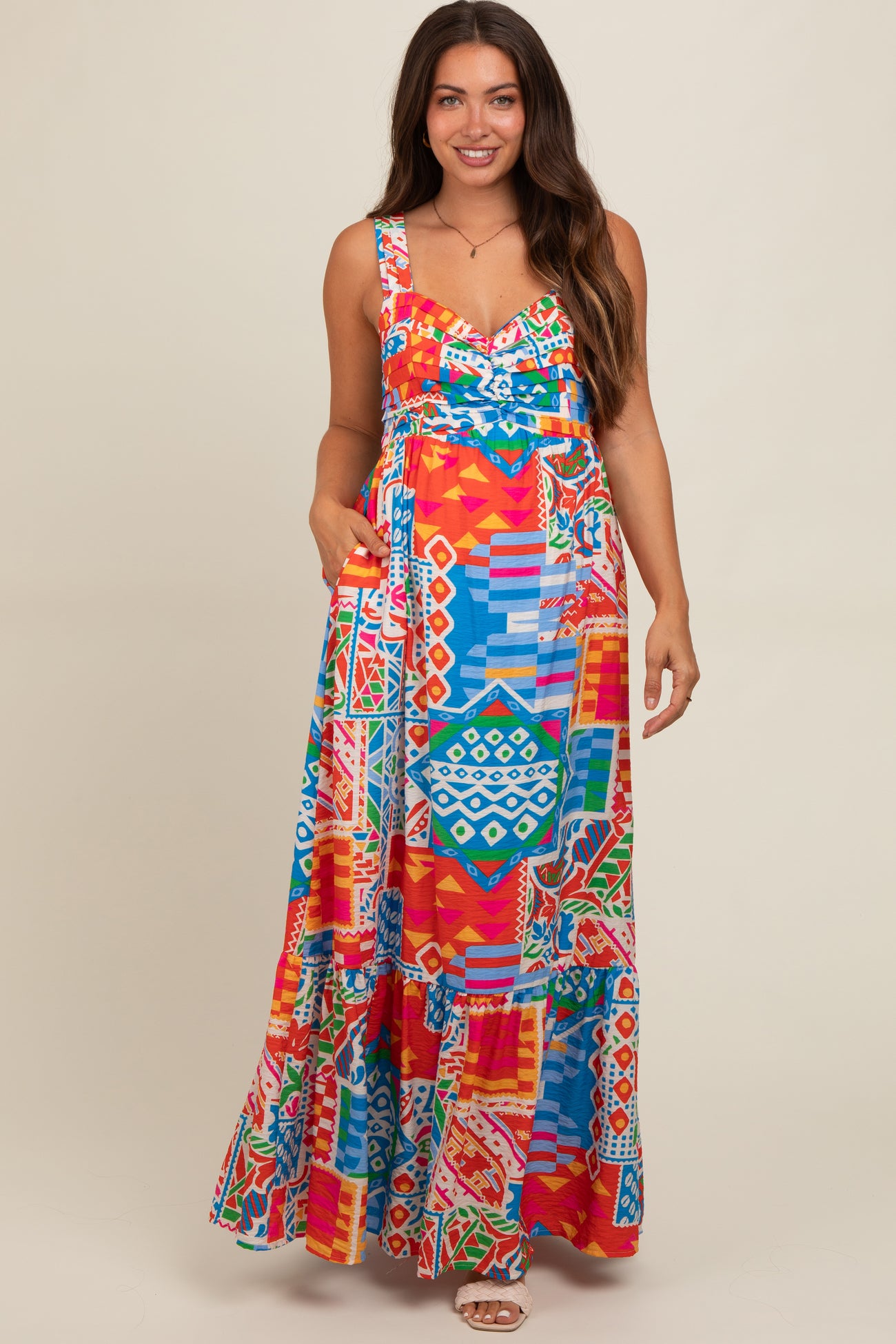 woman wearing a colorful patterned maxi maternity dress with a fitted bodice and pockets, showcasing a baby bump