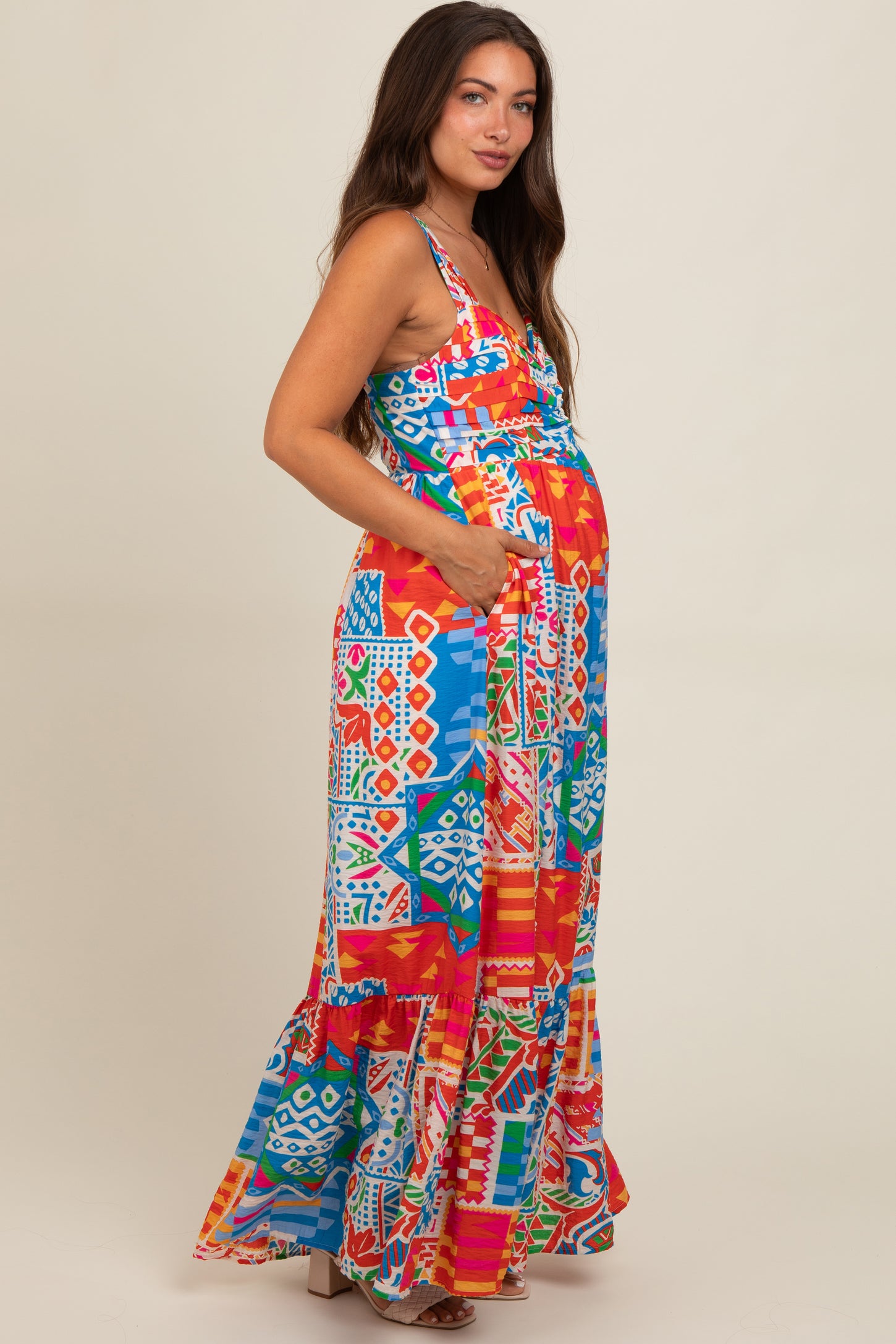 woman wearing a colorful patterned maternity maxi dress with pockets and a visible baby bump