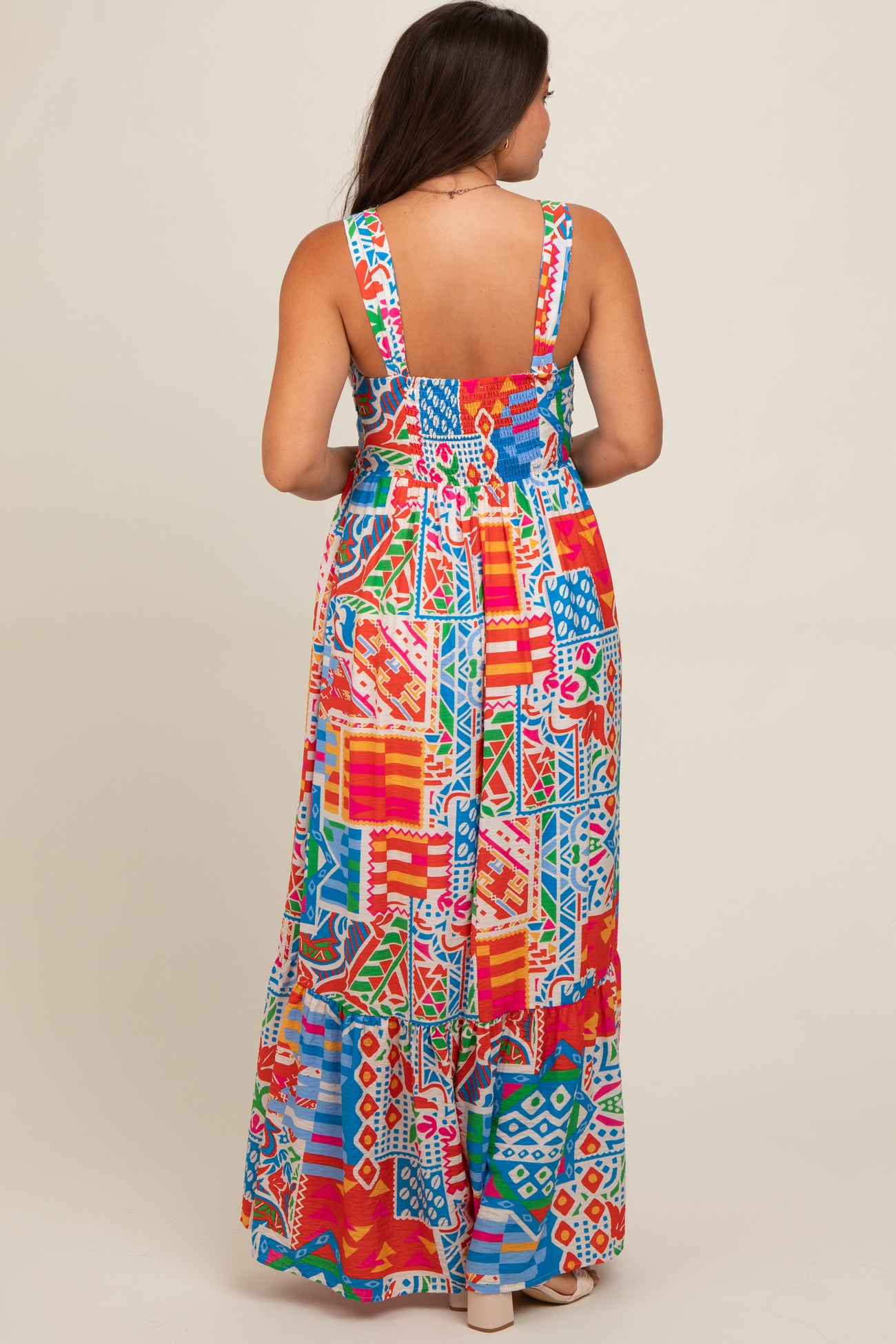 woman wearing a colorful patterned maternity maxi dress with a flowy silhouette and adjustable straps, showing a baby bump