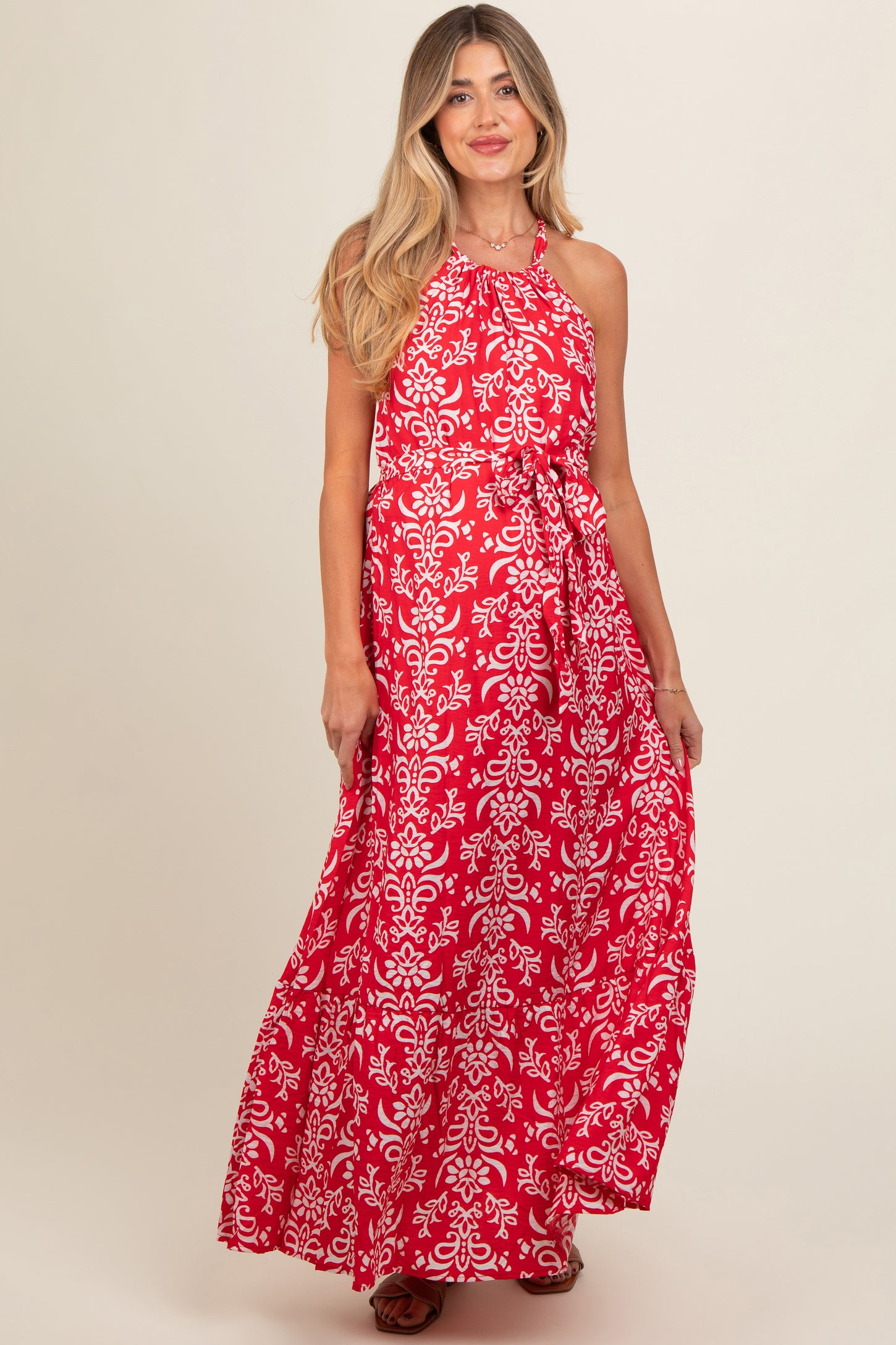 woman wearing a red floral print maternity maxi dress with a halter neckline and a flowing silhouette