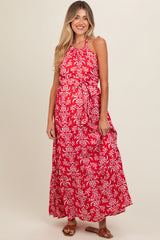 woman wearing a red floral print maternity maxi dress with a halter neckline and tie waist, showing a baby bump