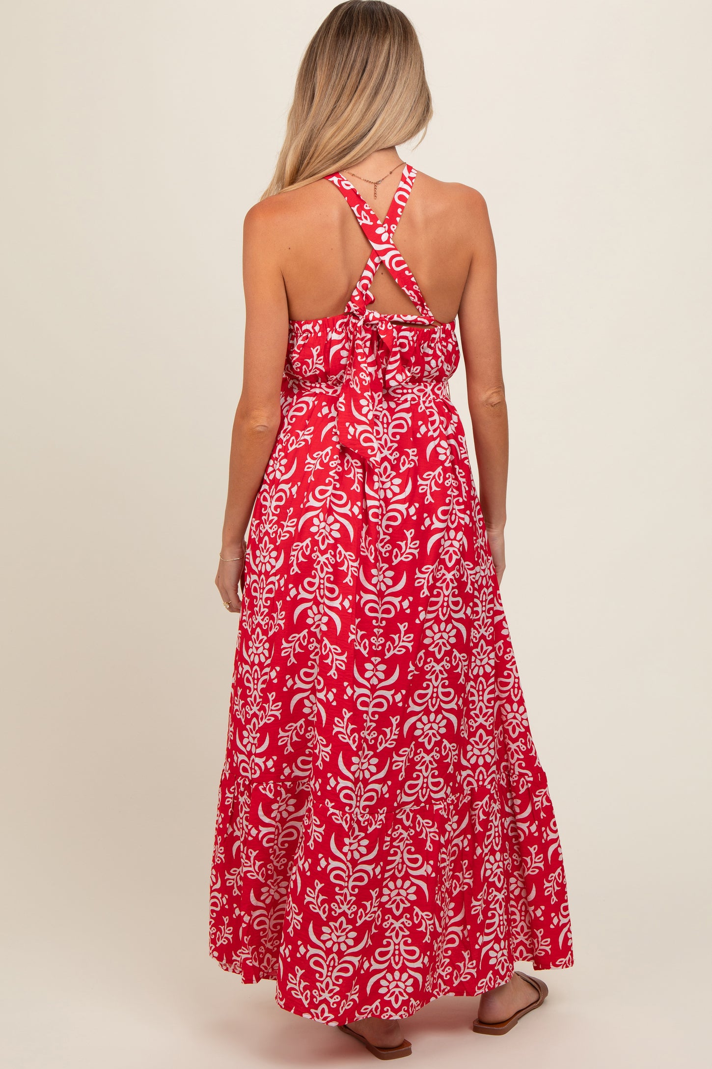 woman wearing a red floral maxi maternity dress with a crisscross back design
