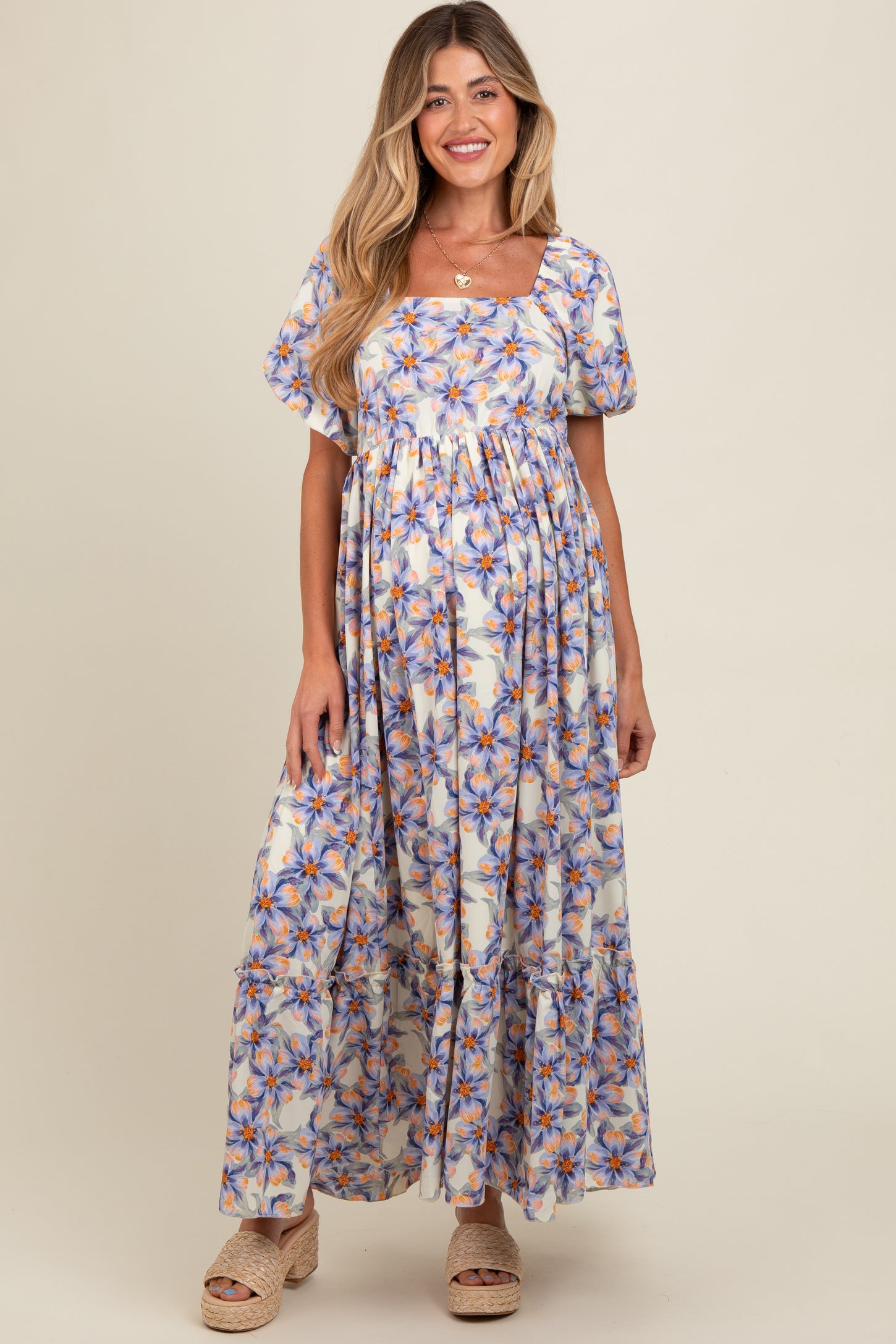 woman wearing a floral maternity maxi dress with puff sleeves and a tiered skirt, showcasing her baby bump