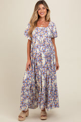 woman wearing a floral maternity maxi dress with puff sleeves and a tiered skirt, showcasing her baby bump