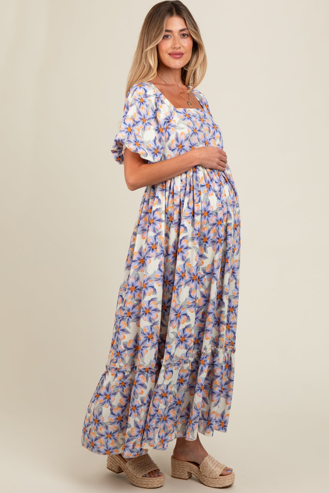 woman wearing a floral print maternity maxi dress and holding her baby bump