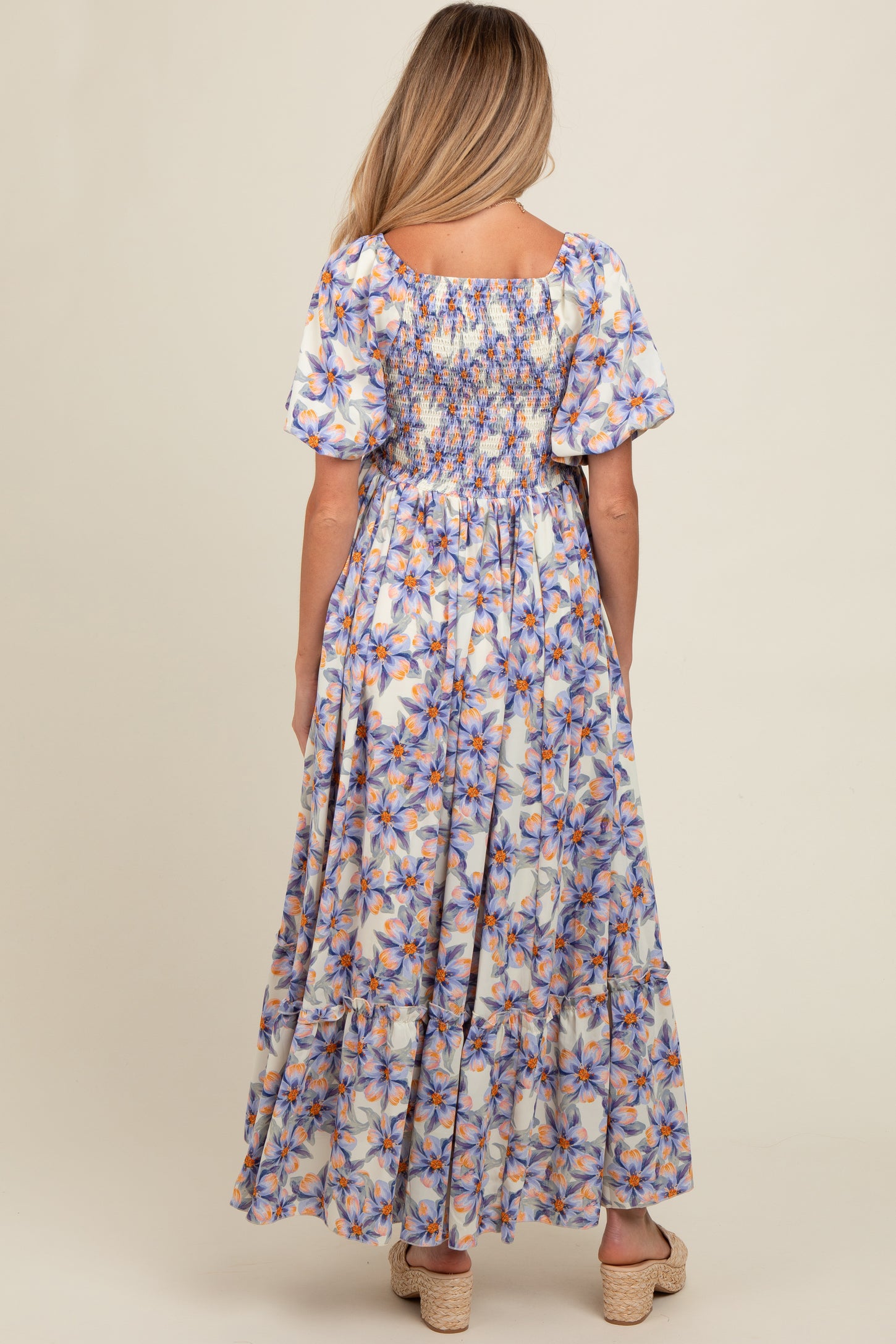 woman wearing a floral maternity maxi dress with puff sleeves and smocked back detail