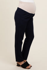 woman wearing navy maternity pants with a belly panel and a visible baby bump, paired with black slide sandals