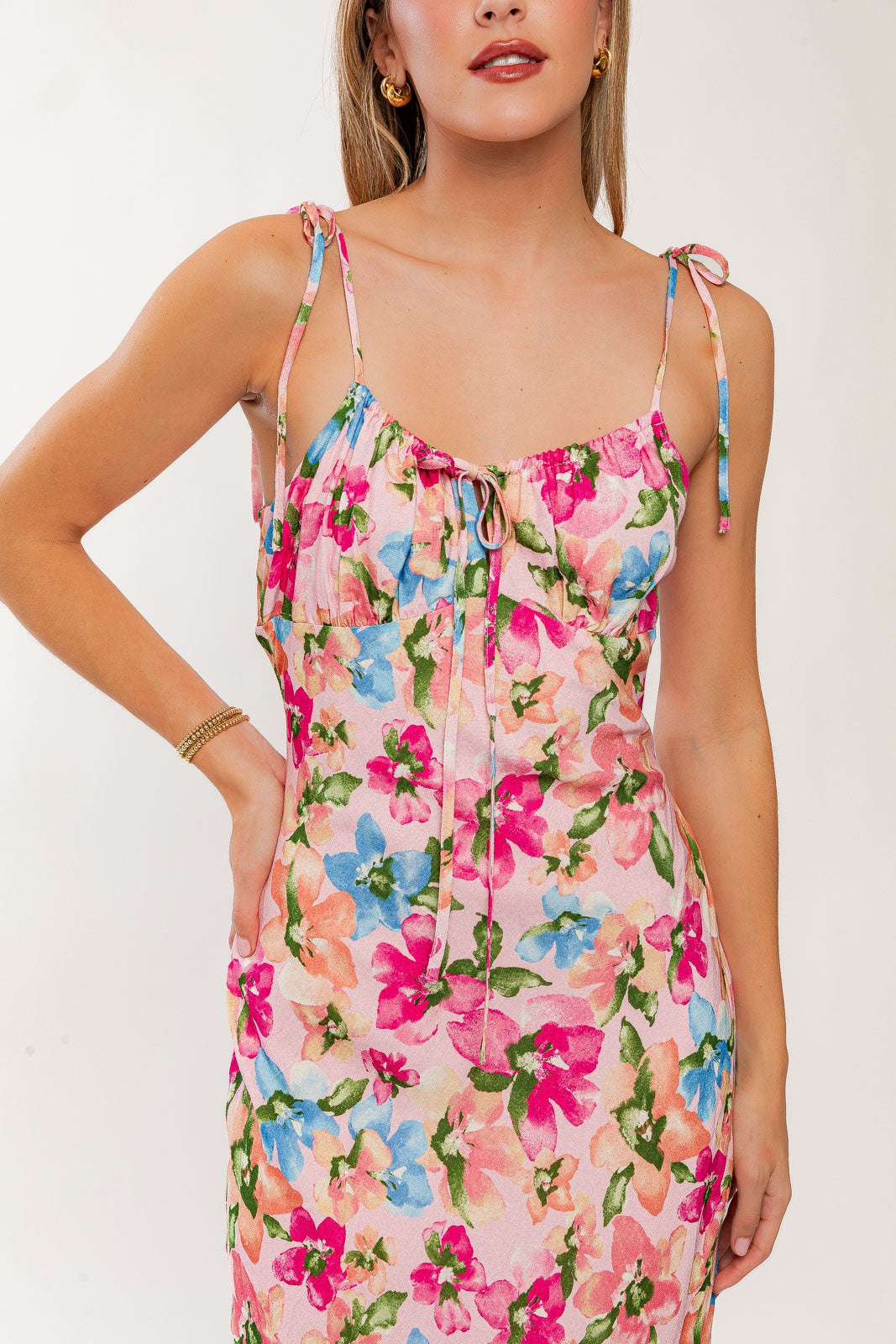 woman wearing a pink floral spaghetti strap dress with tie straps and a ruffled neckline