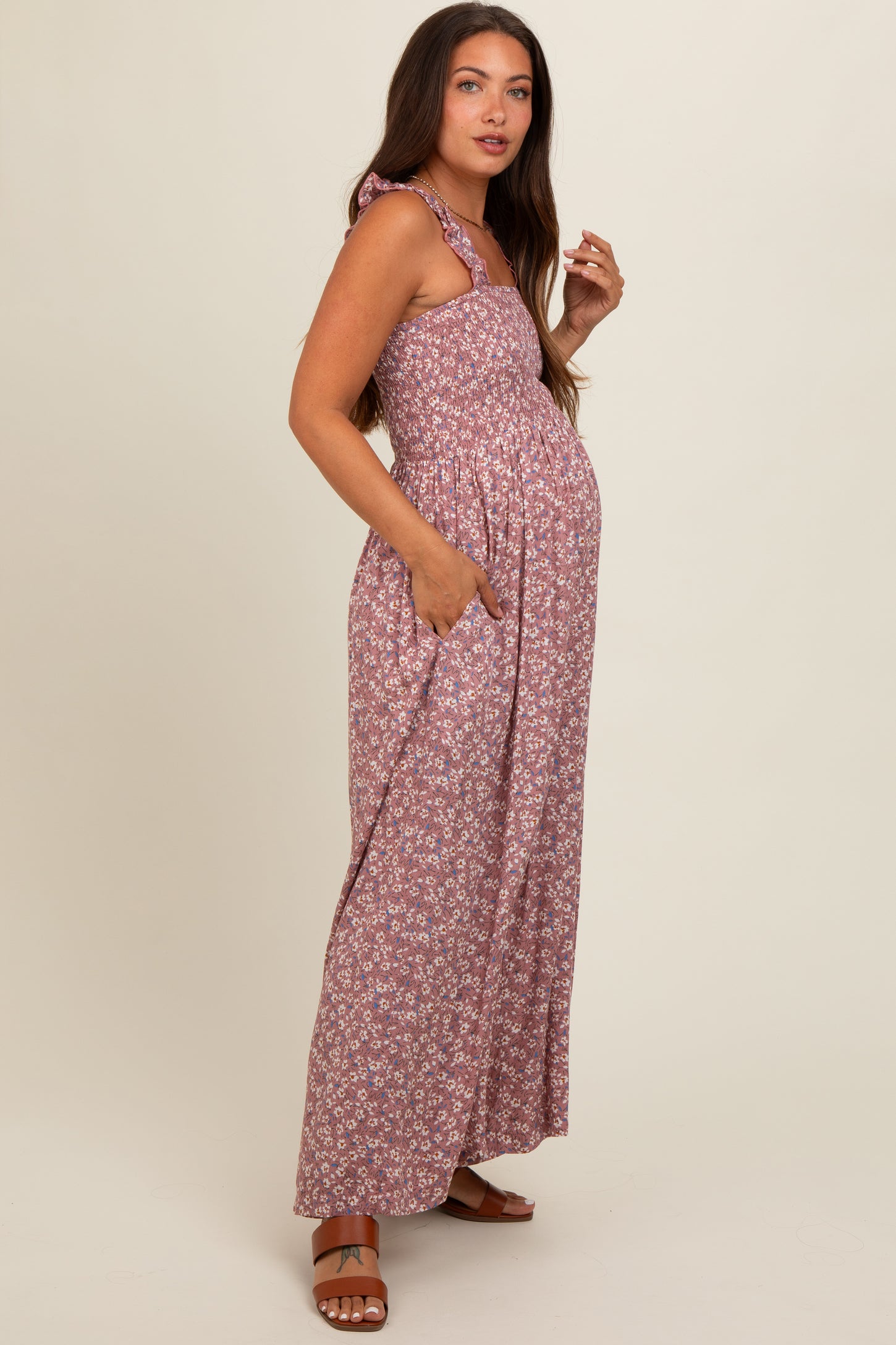 woman wearing a floral maternity maxi dress in mauve with a tie strap and pockets, showcasing her baby bump