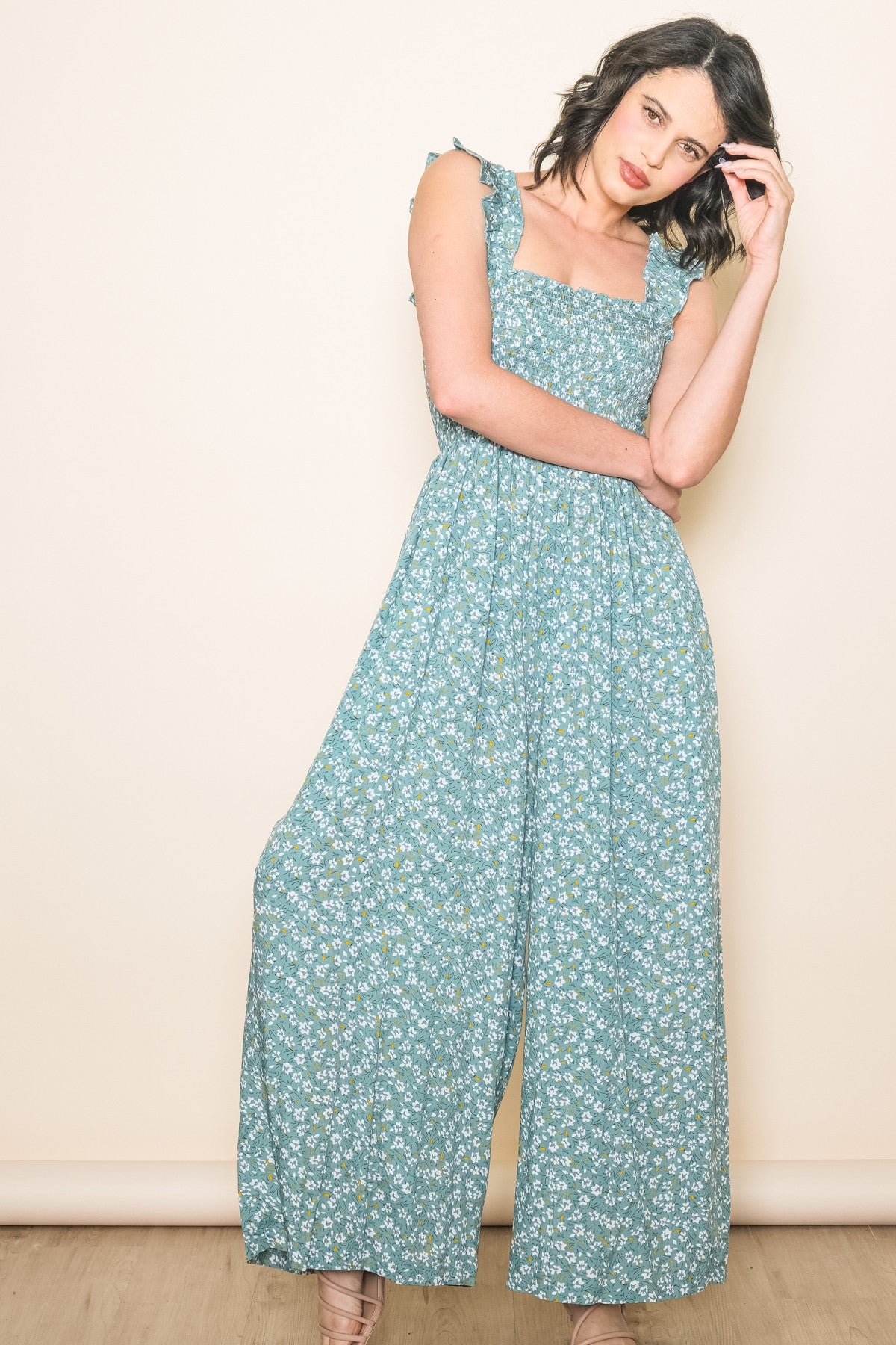 woman wearing a teal floral jumpsuit with ruffled straps and a square neckline