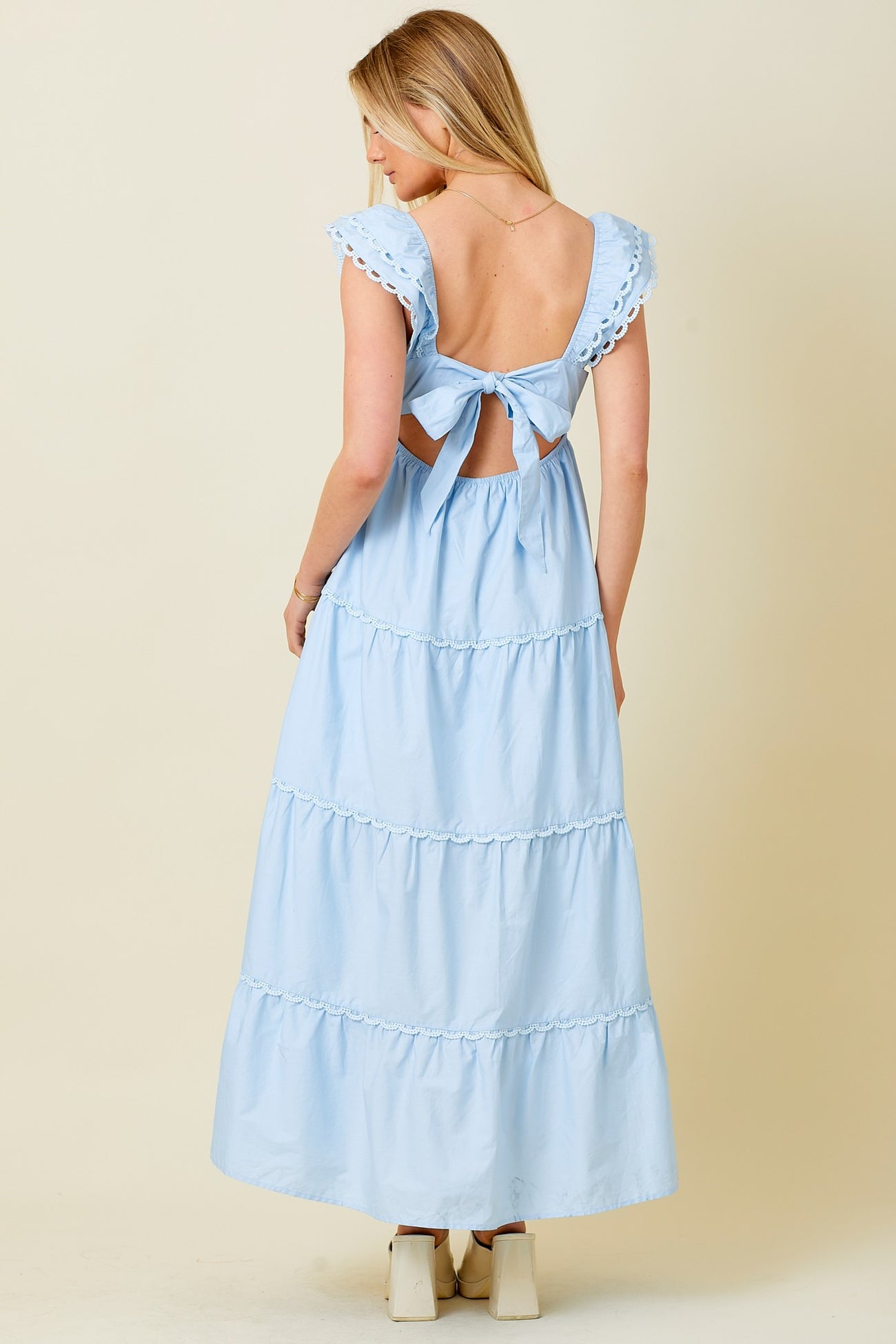 woman wearing a light blue back tie maxi dress with ruffle details and open back design