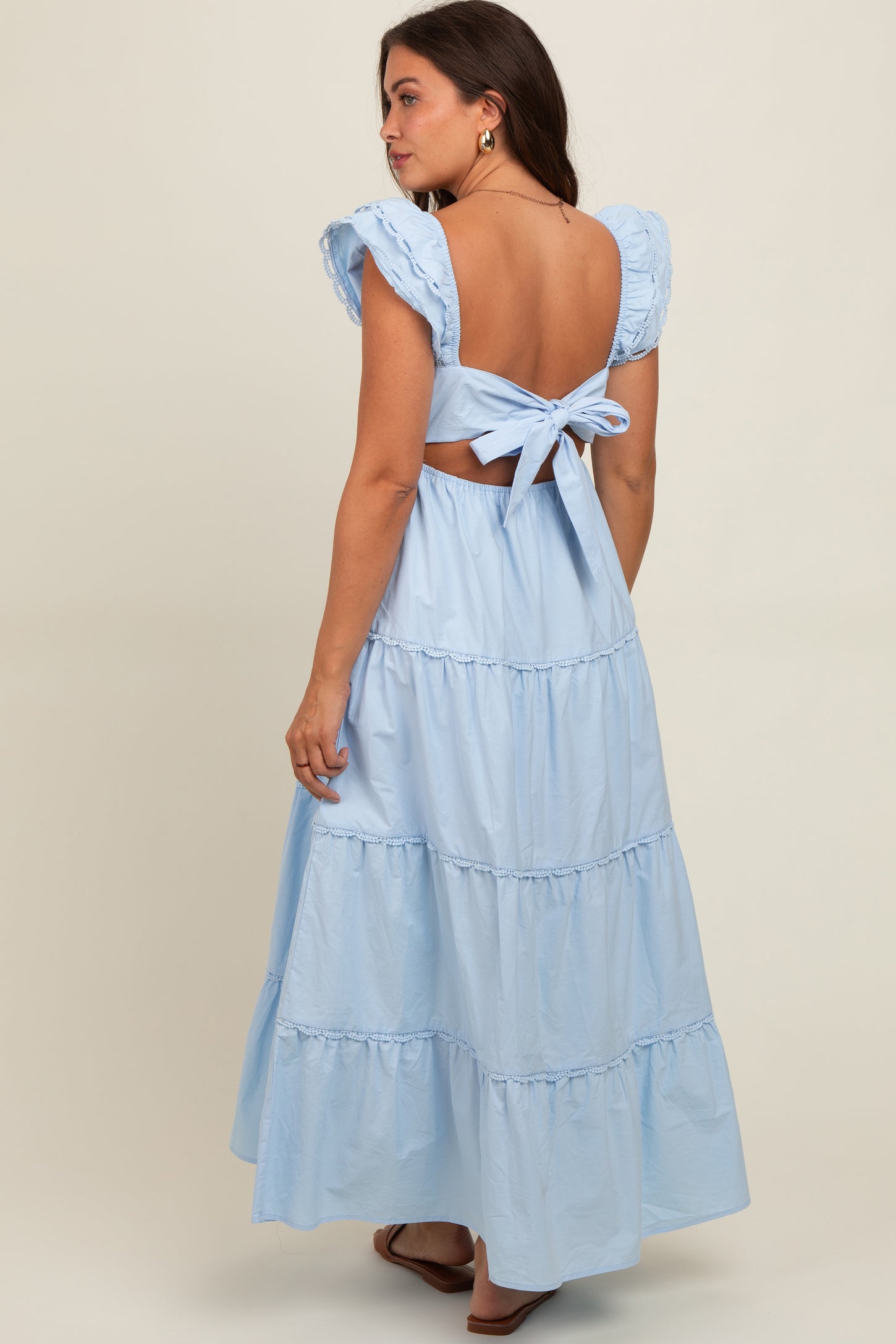 woman wearing a light blue backless maternity dress with ruffle sleeves and a tied waist detail