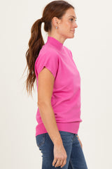 woman wearing a vibrant pink short sleeve mock neck sweater paired with blue jeans