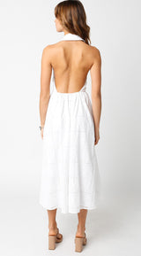 woman wearing a backless white midi dress with an eyelet design, seen from the back